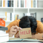 photo d'une personne dont la tête est couchée sur un livre et tend la main avec un carton sur lequel est inscrit en anglais "aidez-moi"