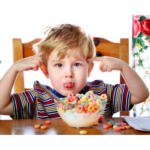 photo d'un enfant qui tire la langue en mangeant un bol de céréales. Plein de céréales ont débordé du bol.