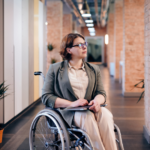 photo d'une femme en fauteuil roulant qui tient un PC portable sur les genoux.